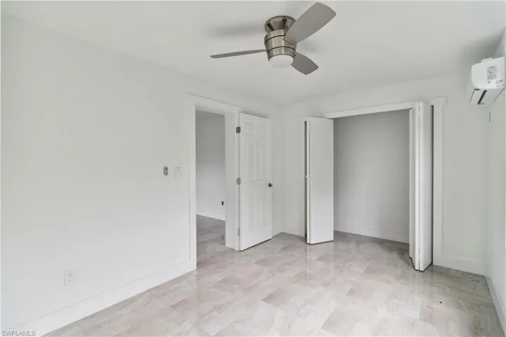 Unfurnished bedroom featuring ceiling fan, a closet, and a wall mounted AC
