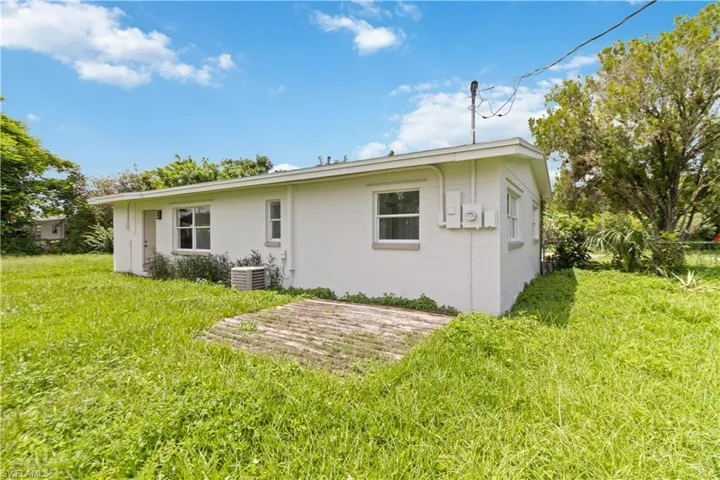 Rear view of property featuring a yard and central air condition unit