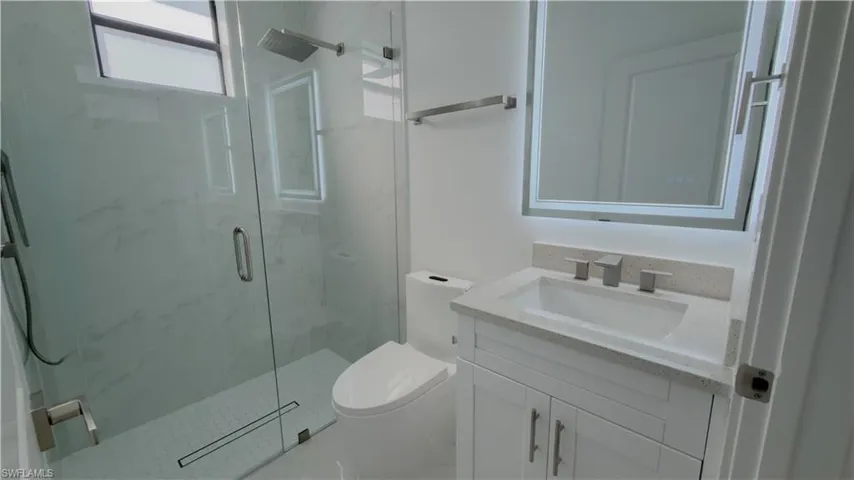 Bathroom featuring vanity and a marble finish shower