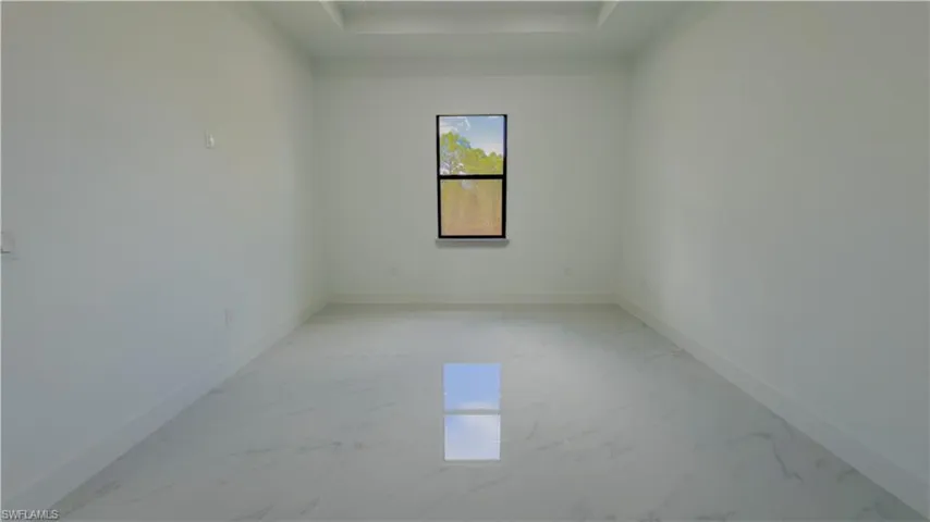 Unfurnished room with light marble finish floors and a tray ceiling