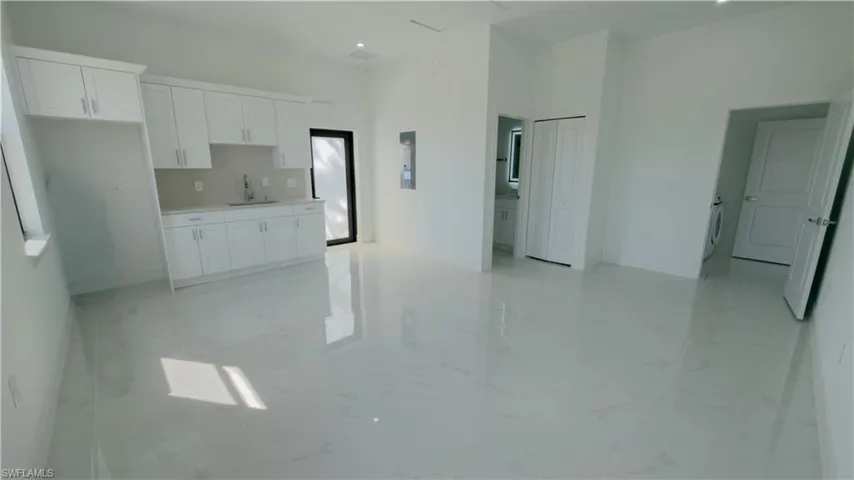Kitchen featuring light countertops, white cabinets, open floor plan, and light marble finish flooring