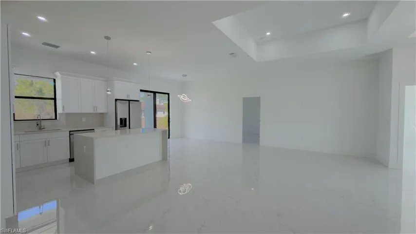 Kitchen featuring white cabinets, a center island, stainless steel appliances, pendant lighting, and open floor plan