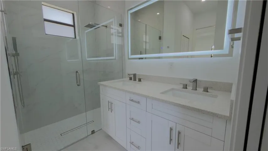 Full bath featuring double vanity and a marble finish shower