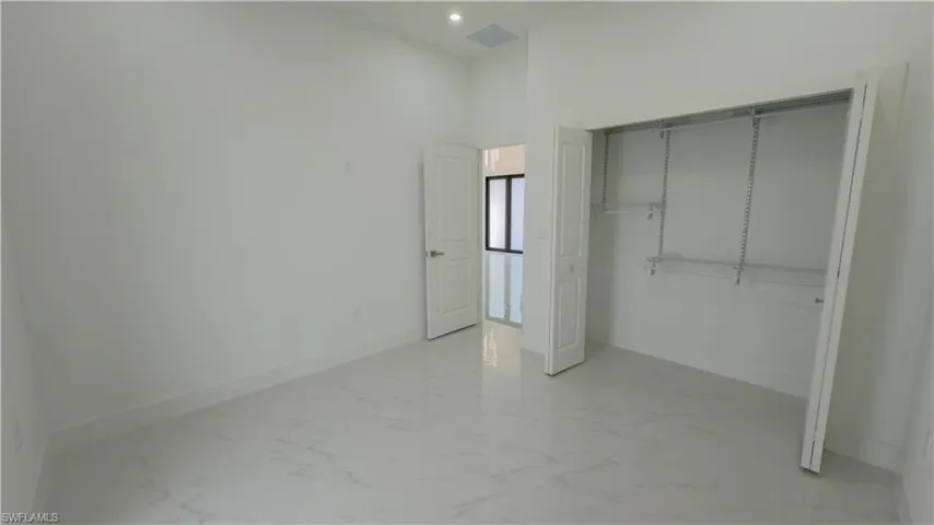 Unfurnished bedroom featuring a closet, a high ceiling, and recessed lighting