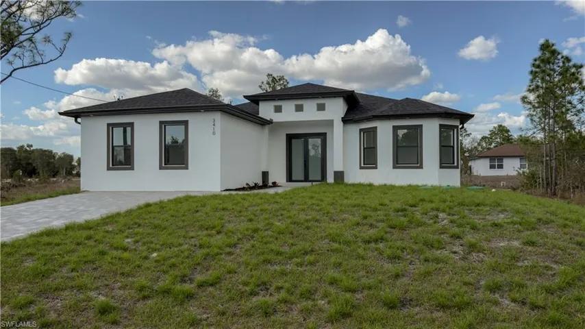 Prairie-style house featuring a front yard, stucco siding, roof with shingles, and a patio area