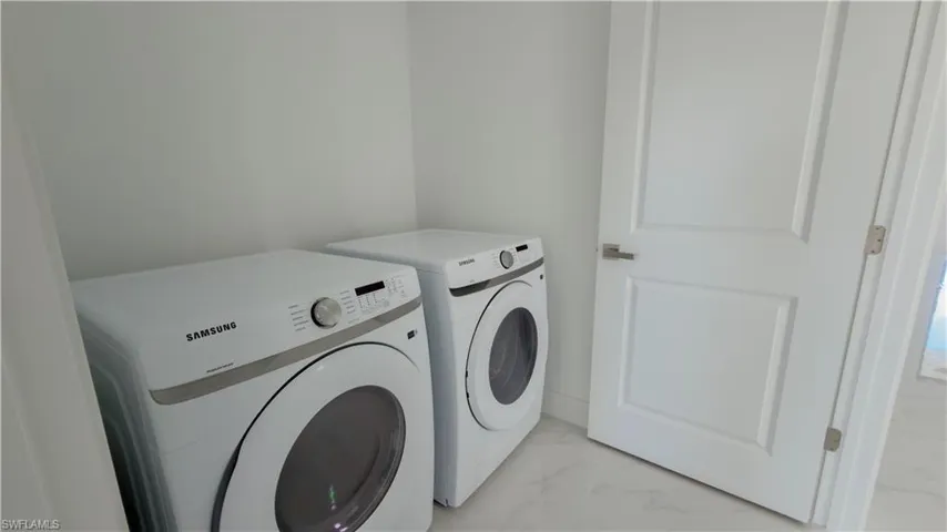 Laundry room featuring light marble finish floors and washing machine and clothes dryer