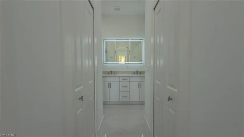 Hall with light marble finish flooring and a sink