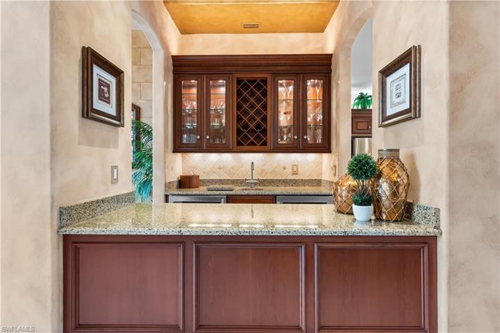 Beverage bar/wet bar offer uplighting/underlighting,custom cherry wood cabinetry,tumbled marble backsplash,refrigerator & wine cellar.