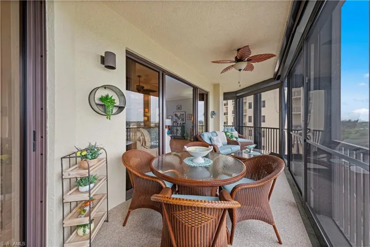 Sunroom with ceiling fan, a textured ceiling, carpet flooring, and a textured wall