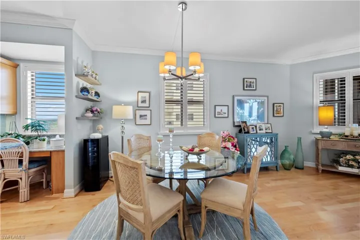 Dining area with a chandelier, plenty of natural light, light wood-type flooring, and crown molding