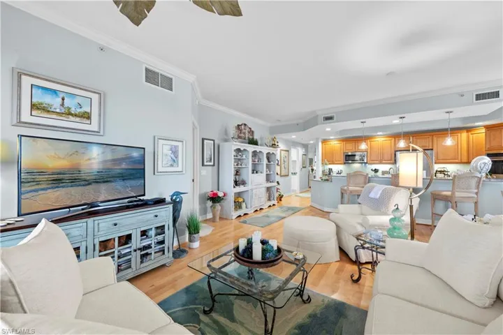 Living room with ornamental molding, light wood finished floors, and recessed lighting