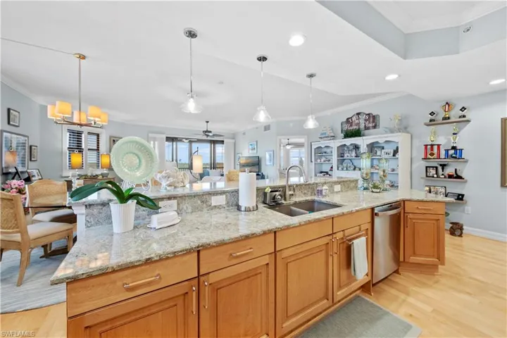 Kitchen with stainless steel dishwasher, crown molding, open floor plan, light wood-type flooring, and recessed lighting