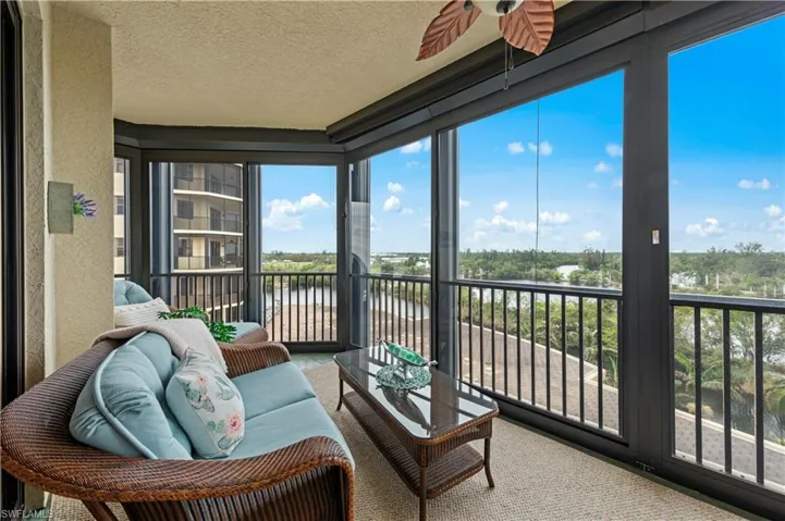 Sunroom / solarium featuring ceiling fan, a water view, a textured ceiling, and carpet flooring