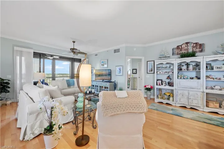 Living area with crown molding, a ceiling fan, and wood finished floors