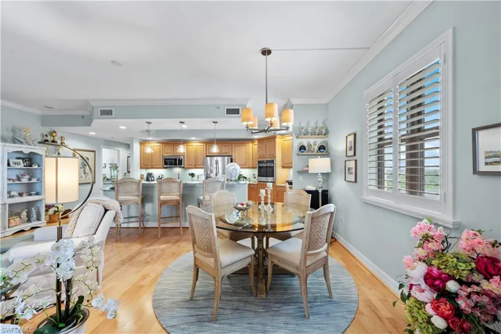 Dining area with a chandelier, light wood-type flooring, and ornamental molding