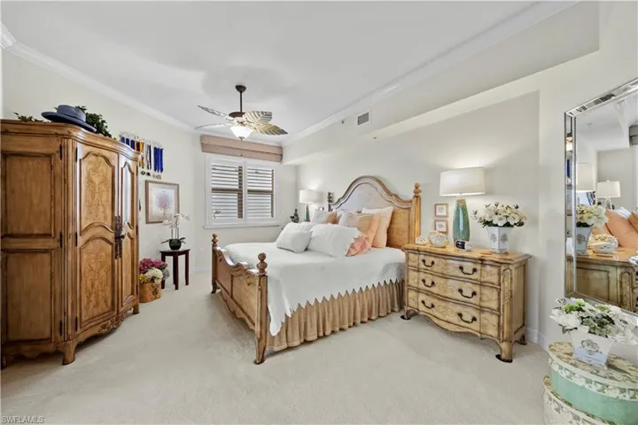 Bedroom with light carpet, ornamental molding, and ceiling fan
