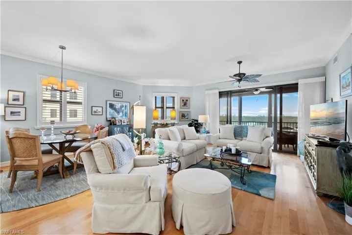 Living room with a chandelier, light wood finished floors, crown molding, and ceiling fan
