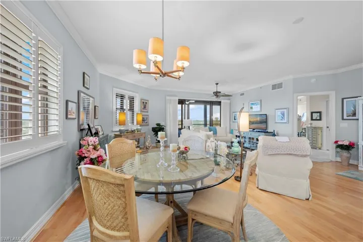 Dining space with a chandelier, light wood-style flooring, ornamental molding, and a ceiling fan