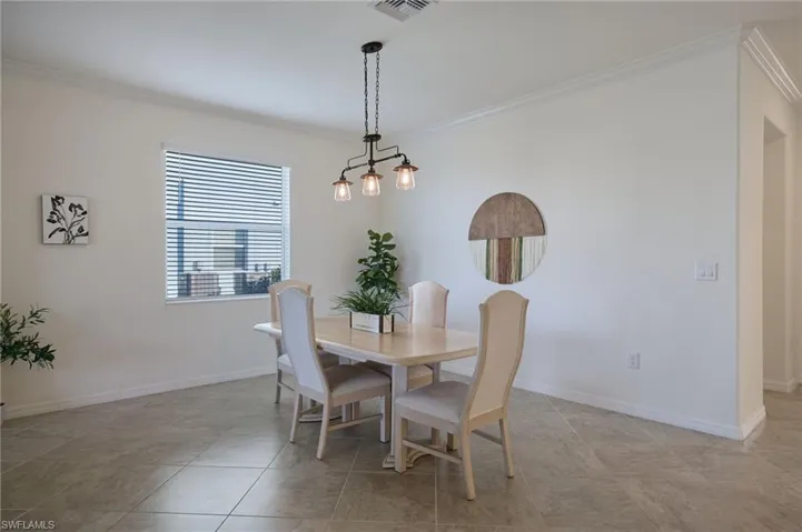 Dining area featuring ornamental molding and light tile patterned floors