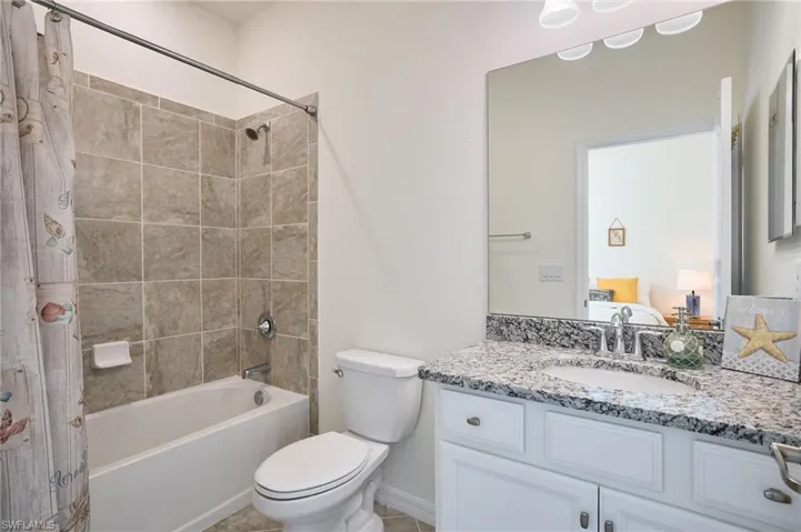 Full bathroom featuring tiled shower / bath, vanity, and toilet