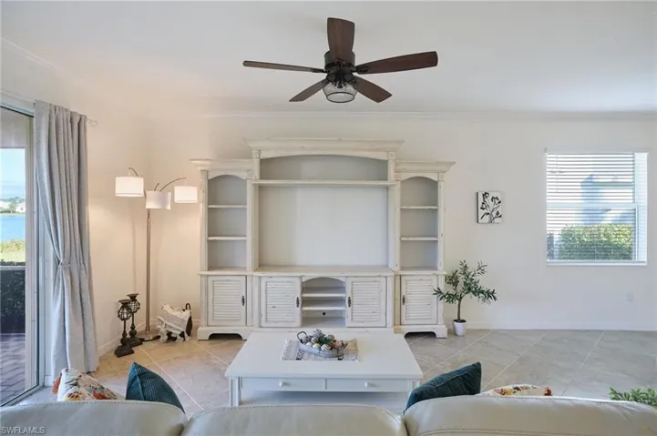 Tiled living room featuring ceiling fan and ornamental molding
