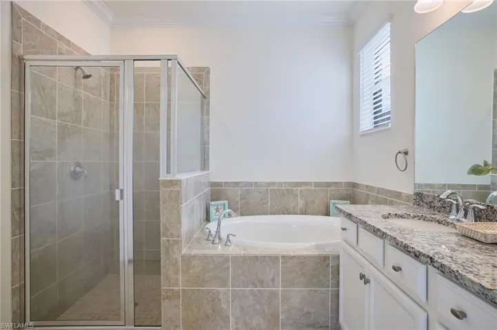Owners ensuite bathroom with dual vanity, crown molding, and separate shower and tub