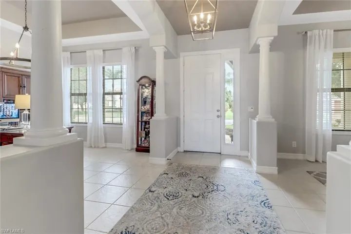 Entryway with decorative columns, light tile patterned floors, and a chandelier