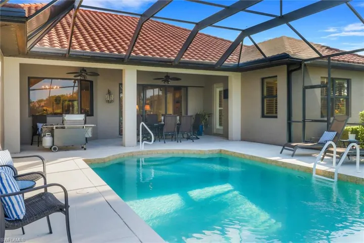 Outdoor pool with a patio area, a ceiling fan, a lanai, and exterior kitchen