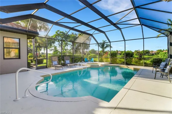 View of swimming pool featuring a patio area, a pool with connected hot tub, and glass enclosure