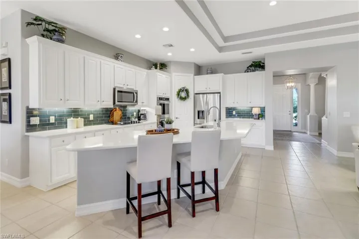 Kitchen featuring decorative backsplash, light tile patterned floors, a spacious island, light countertops, and recessed lighting