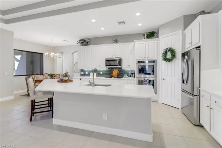 Kitchen featuring stainless steel appliances, backsplash, a chandelier, recessed lighting, and a kitchen island with sink