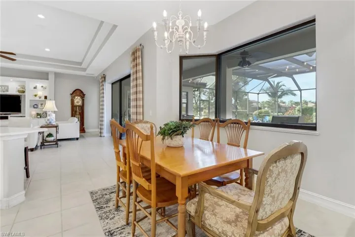 Dining room with a ceiling fan, a chandelier, light tile patterned floors, and a raised ceiling