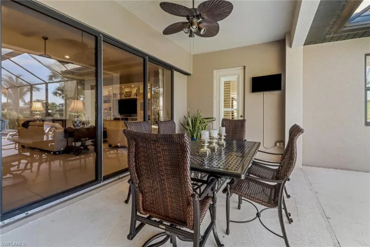 View of patio with a ceiling fan, outdoor dining area, and glass enclosure