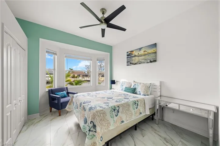 Bedroom featuring light marble finish flooring, a ceiling fan, and a closet