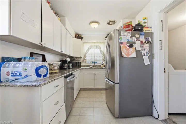 Kitchen featuring white cabinets, appliances with stainless steel finishes, washer / dryer, and dark stone counters