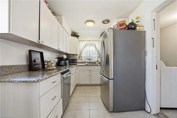 Kitchen featuring white cabinets, appliances with stainless steel finishes, dark stone countertops, and washer / dryer
