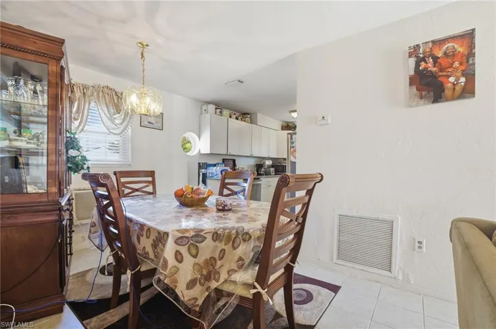 Dining area featuring light tile patterned floors, a chandelier, and a textured wall
