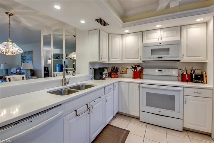 Kitchen featuring pendant lighting, sink, white appliances, and white cabinets
