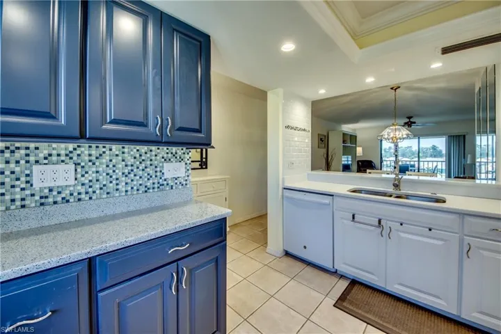 Kitchen featuring dishwasher, sink, light tile patterned floors, and blue cabinetry