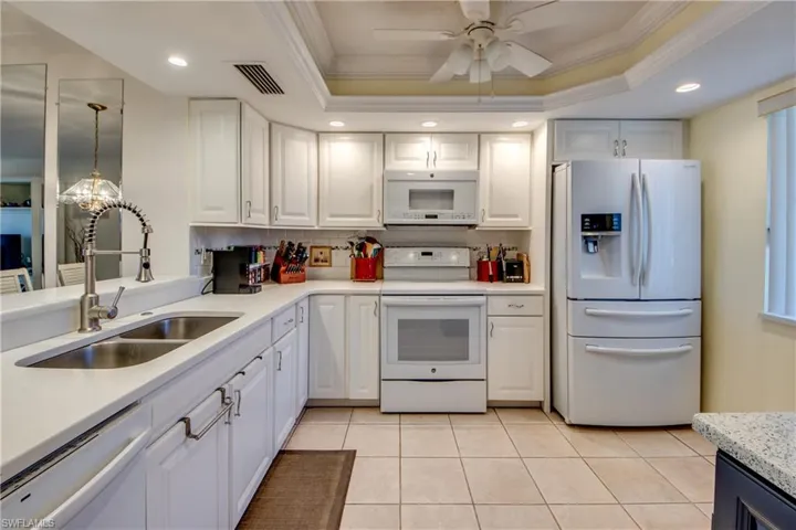 Kitchen featuring a tray ceiling, white appliances, and white cabinetry