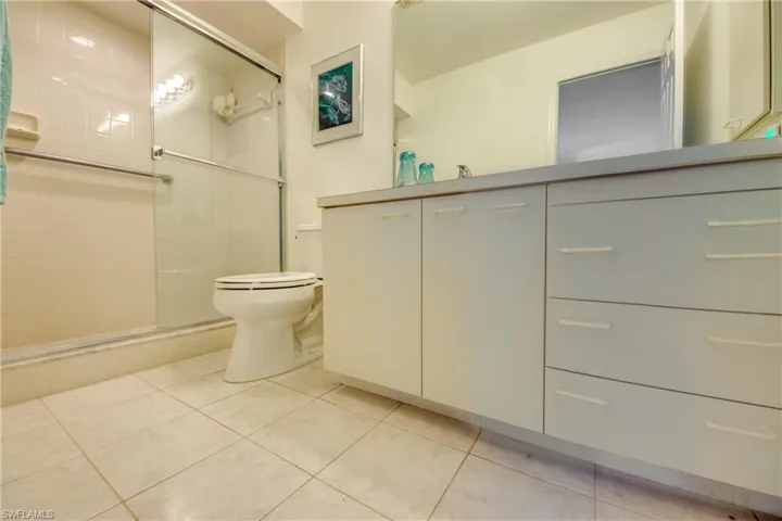 Bathroom with a shower with door, vanity, tile patterned floors, and toilet