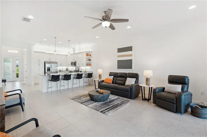 Tiled living room featuring ceiling fan and ornamental molding