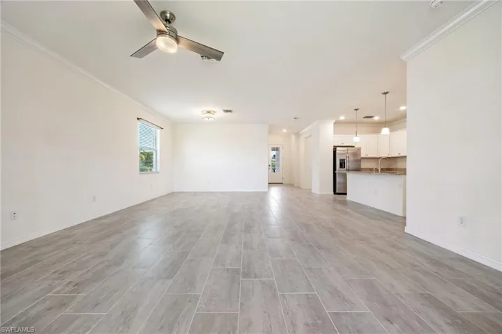 Unfurnished living room featuring crown molding, a ceiling fan, recessed lighting, light wood-style flooring, and baseboards