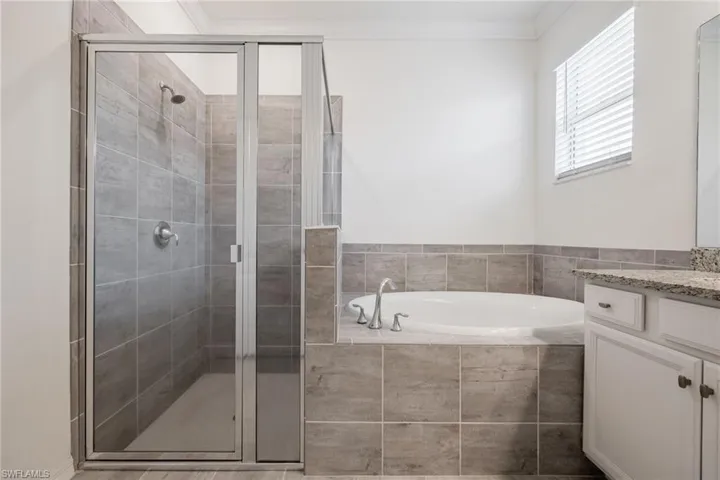Full bath with a garden tub, vanity, a stall shower, and crown molding
