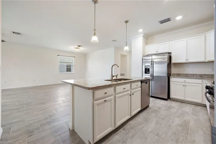 Kitchen with a sink, appliances with stainless steel finishes, crown molding, wood finish floors, and light stone countertops