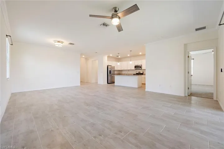 Unfurnished living room featuring a ceiling fan, crown molding, baseboards, and recessed lighting