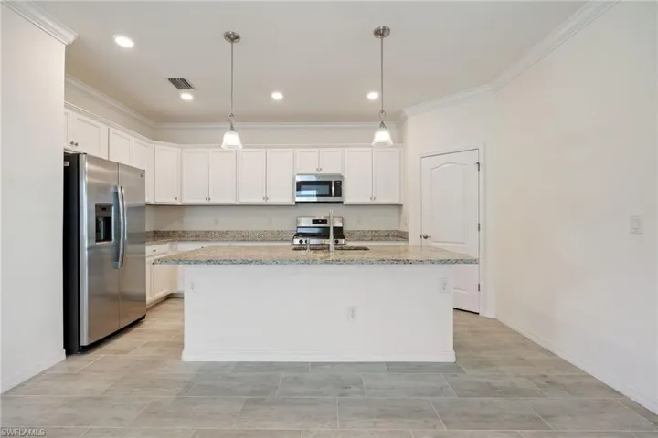 Kitchen featuring stainless steel appliances, ornamental molding, white cabinetry, baseboards, and recessed lighting