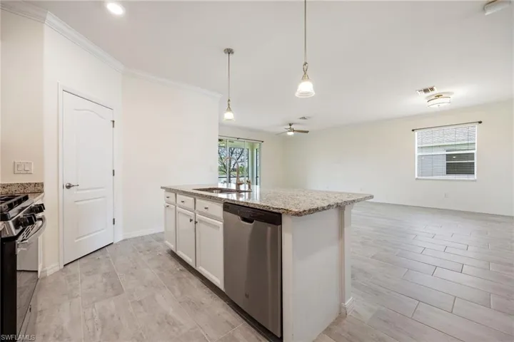 Kitchen featuring dishwasher, range, a sink, crown molding, and open floor plan