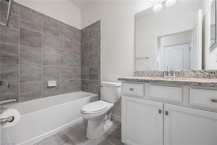 Full bathroom with toilet, vanity, tub / shower combination, and baseboards