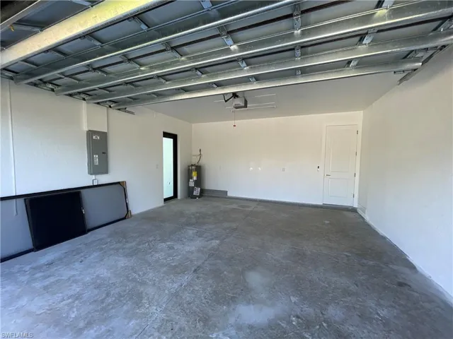 Garage with electric panel, a garage door opener, and water heater